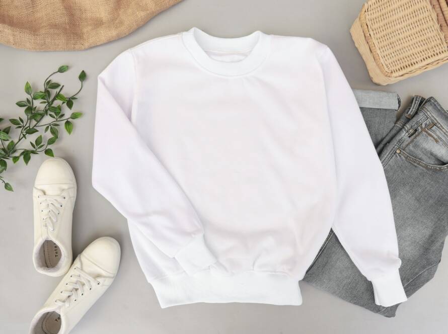 White sweatshirt displayed flat with shoes and jeans
